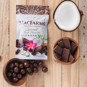 
            
                Load image into Gallery viewer, coconut dark chocolate macadamias - MacFarms on wood table with coconut, bowl of chocolate, and bowl of coconut dark chocolate macadamias
            
        
