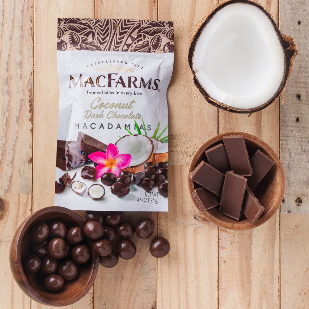 
            
                Load image into Gallery viewer, coconut dark chocolate macadamias - MacFarms on wood with coconut, bowl of dark chocolate, and bowl of coconut dark chocolate macadamias
            
        