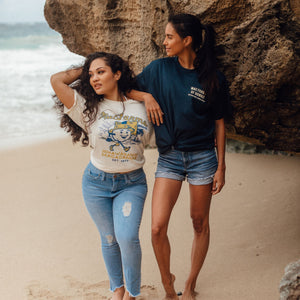 two woman on beach with one wearing MacFarms character t-shirt in vintage white