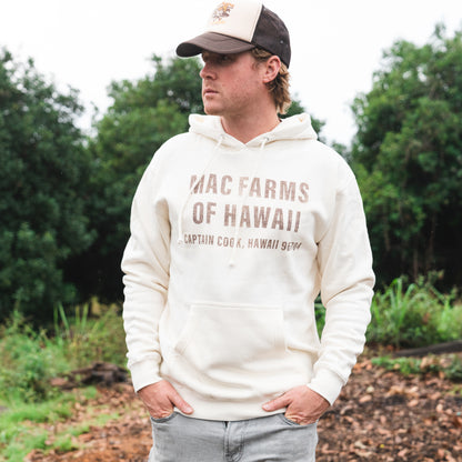 man standing wearing off white hoodie with "mac farms of hawaii" on it 