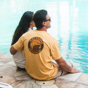 man sitting with woman by pool wearing gold mac farms shirt 