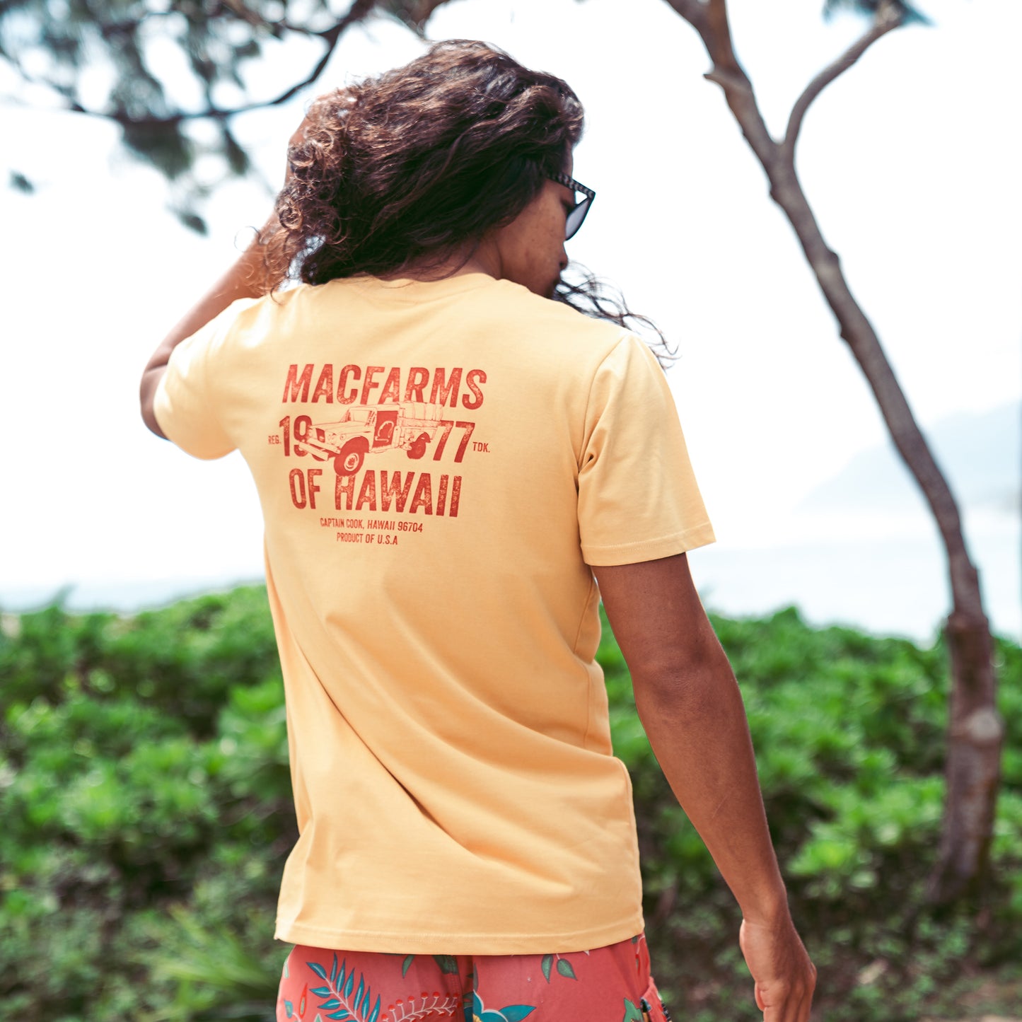 man wearing mustard t-shirt with "mac farms of hawaii" truck graphic