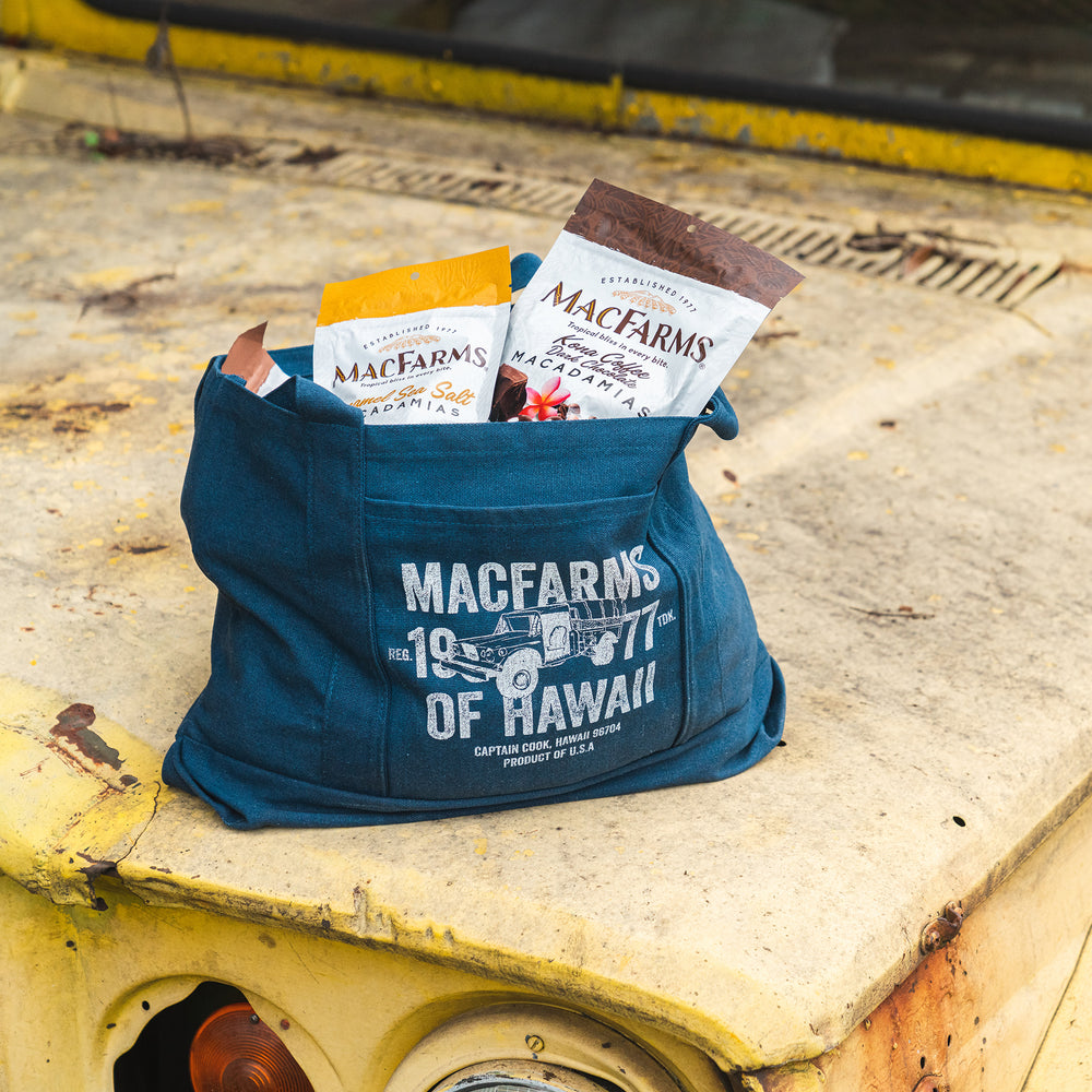 blue tote bag with "mac farms 1977 of hawaii" and car design with mac farm nuts in the bag