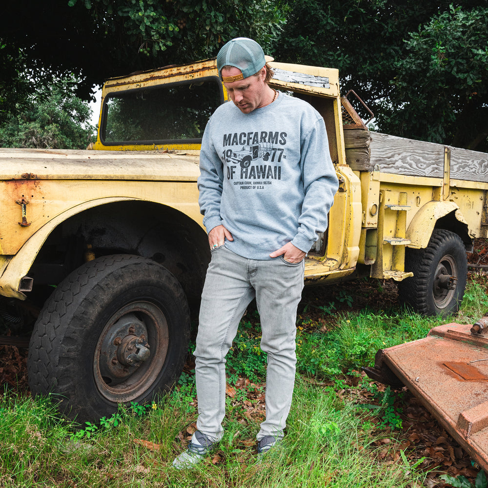 man standing in front of truck with grey crewneck on 